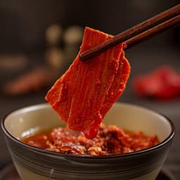 Chopsticks lifting a glossy latiao strip